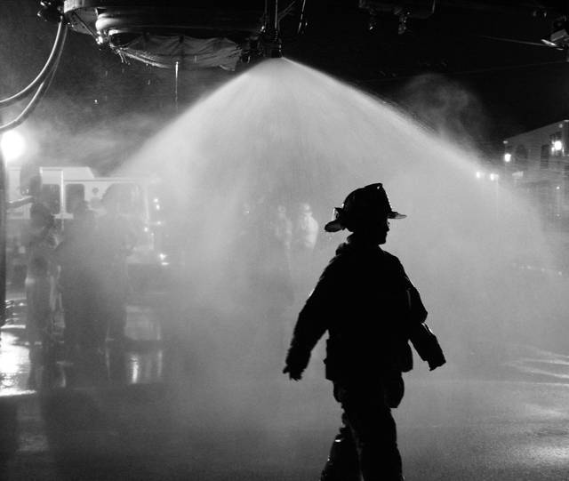 A young firefighter silhouetted in the spray